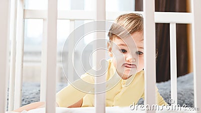 Portrait of a bored child sitting in a crib in a nursery Stock Photo