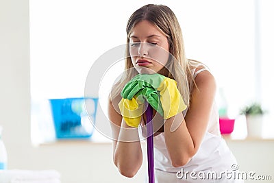 Boring young woman holding broom while cleaning at home. Stock Photo