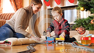 Portrait of boy with his mother playing on floor with toy train and railways. Child receiving presents and toys on New Stock Photo