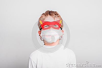 Portrait of boy in superhero mask with his mouth covered with a medical mask to protect himself from viral infections and diseases Stock Photo