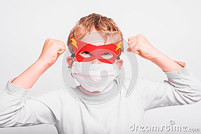 Portrait of boy in superhero mask with his mouth covered with a medical mask to protect himself from viral infections and diseases Stock Photo