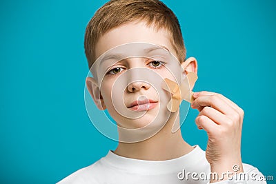 Portrait of a boy tearing off adhesive plaster from his che Stock Photo
