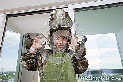 Portrait of boy wearing dinosaur costume relaxing on sofa at home Stock Photo