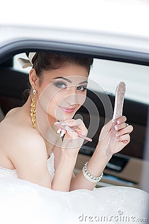 Portrait of the bride. Sits in the car, looks in the mirror. Makeup Wedding day Stock Photo