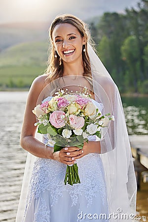 Portrait, bride and smile with flower bouquet at lake, nature and celebration of commitment, love and marriage. Happy Stock Photo