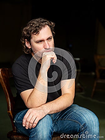 Portrait of brooding man, sitting on chair Stock Photo