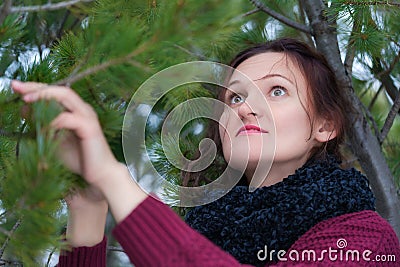 Portrait of brunette woman with long hair and brown eyes standing in pine forest. Cute young woman dressed in brown Stock Photo