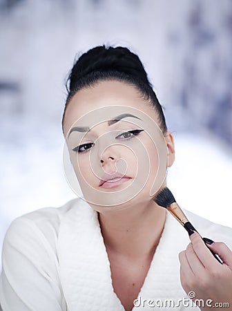 Portrait of a brunette woman putting on make up in front of the mirror Stock Photo