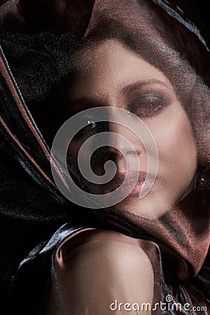 Portrait of a brunette woman through a transparent dark fabric. Beauty and makeup girl. There is no focus Stock Photo
