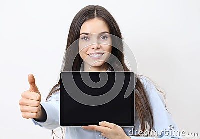 Portrait of brunette young smiling woman holding a tablet with blank screen showing thumb up and looking at camera isolated on Stock Photo