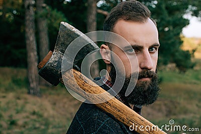 Portrait brutal bearded and moustached woodcutter hipster Gypsy man in the forest with ax Stock Photo