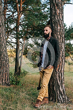 Portrait brutal bearded and moustached woodcutter hipster Gypsy man in the forest with ax Stock Photo