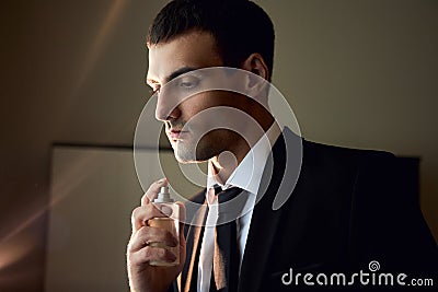 Portrait of a brutal man with Cologne in his hands, perfume fragrance for real men, perfume cosmetics. Perfume cologne bottle. Stock Photo