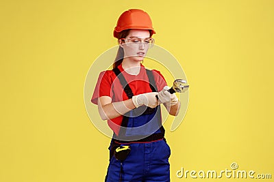 Builder woman working with adjustable wrench, looking with serious concentrated expression. Stock Photo
