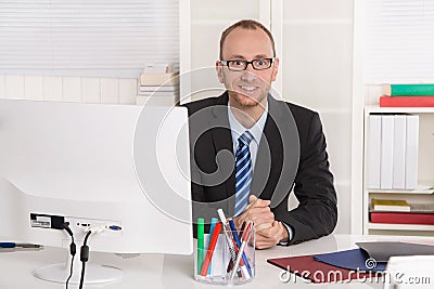 Portrait: Businessman sitting in his office with suit and tie. Stock Photo