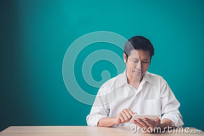 Portrait of businessman smiling and using pad at desktop against of blue wall. Stock Photo