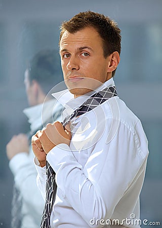 Portrait of businessman tying tie Stock Photo