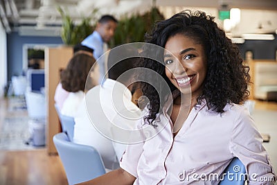 Portrait Of Businesswoman In Modern Office With Colleagues Meeting Around Table In Background Stock Photo