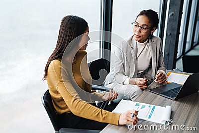 Portrait of businesswomen sitting by desk while working in office Stock Photo