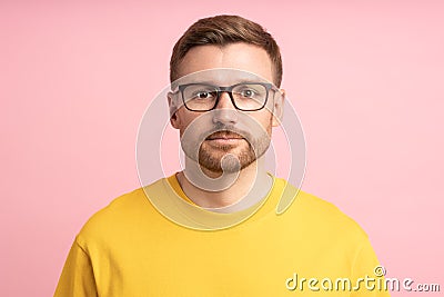 Portrait calm pensive bearded middle aged man in glasses looking at camera on pink background. Stock Photo