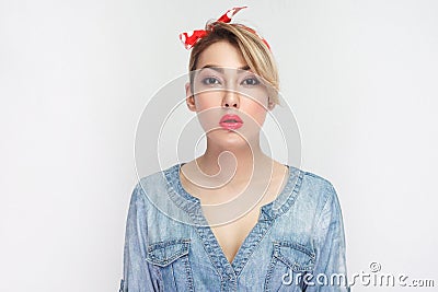 Portrait of calm serious beautiful young woman in casual blue denim shirt with makeup and red lips and headband standing and Stock Photo