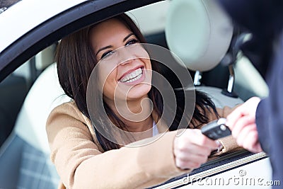 Car rental agency employee giving car keys to beautiful young woman. Stock Photo