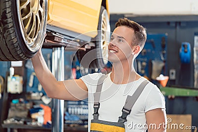 Portrait of a car tuning specialist smiling while checking wheels of tuned car Stock Photo