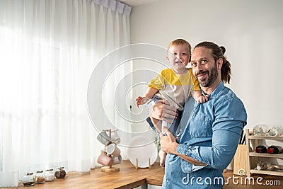 Portrait of Caucasian loving father hold baby boy child in living room. Happy family, attractive caring young dadd carry his Stock Photo