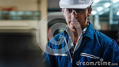 Portrait of caucasian man industrial worker or labor in blue factory uniform with white safty helmet in factory metal workshop Stock Photo