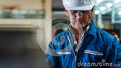 Portrait of caucasian man industrial worker or labor in blue factory uniform with white safty helmet in factory metal workshop Stock Photo