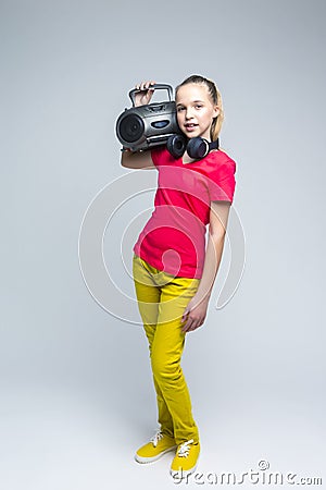 Portrait of Caucasian teenager Girl with Portable Taperecorder. Standing Over Gray background Stock Photo