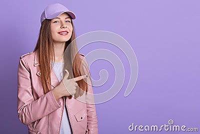 Portrait of charismatic stylish young female raising hand, making gesture, showing direction with forefinger, wearing t shirt, Stock Photo