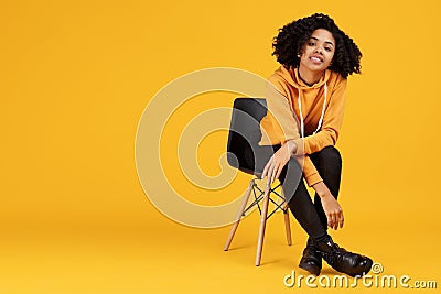 Portrait of charming african american young woman with beautiful smile dressed in casual clothes sitting on the stylish Stock Photo