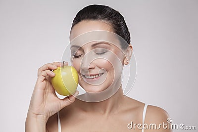 Portrait of charming beautiful healthy caucasian middle aged woman holding green apple, she love to eat fruit, make her get good Stock Photo