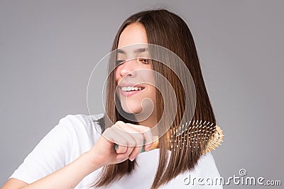 Portrait of charming brunette hair lady combing hair with hairbrush comb, isolated. Young beautiful woman brush long Stock Photo