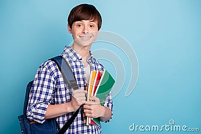 Portrait of charming college student holding note books looking wearing checked shirt isolated over blue background Stock Photo