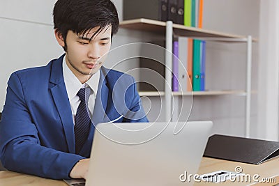 Portrait charming handsome young businessman. Attractive handsome business man is working on laptop computer at office on desk. H Stock Photo