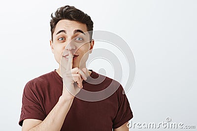 Portrait of charming playful male student in casual trendy t-shirt, lifting eyebrown with happy friendly expression Stock Photo