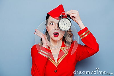 Vintage stewardess wearing in red uniform with alarm clock Stock Photo