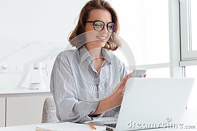 Portrait of charming woman in glasses and striped shirt using mo Stock Photo