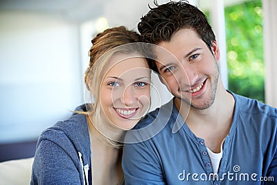 Portrait of cheeful young couple sitting at home Stock Photo