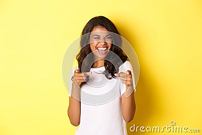 Portrait of cheeky, beautiful african-american woman in white t-shirt, winking and pointing fingers at camera to say Stock Photo