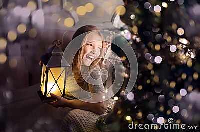 Portrait of a cheerful cute girl near a Christmas tree with a lantern. New Year holidays Stock Photo