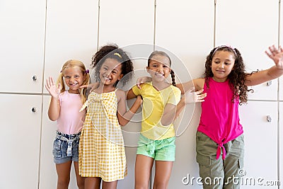 Portrait of cheerful cute multiracial elementary schoolgirls with arm around waiting while standing Stock Photo