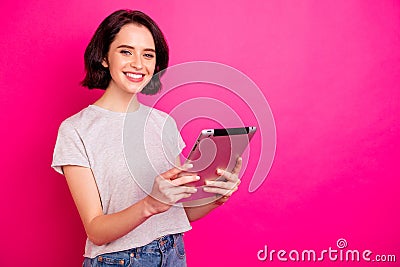 Portrait of cheerful excited freelancer using tablet searching news wearing white t-shirt isolated over pink fuchsia Stock Photo