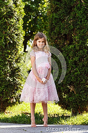 Portrait of a cheerful girl in a lush pink dress in the park. Stock Photo