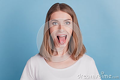 Portrait of cheerful healthy girl look camera protrude tongue on blue background Stock Photo