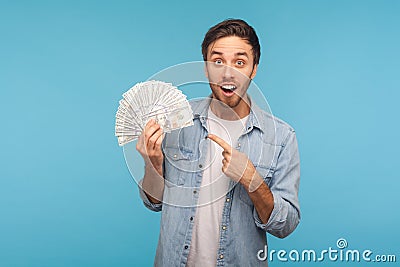 Portrait of cheerful naive surprised man in worker denim shirt pointing dollar banknotes and looking at camera Stock Photo