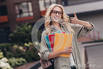 Portrait of cheerful nice lady hold materials supplies hand finger demonstrate thumb up street outside Stock Photo