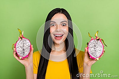 Portrait of cheerful person hold two halves dragonfruit toothy smile look camera isolated on green color background Stock Photo